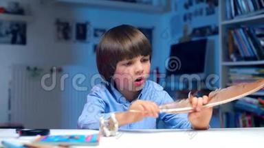 一个孩子坐在<strong>幼儿园</strong>的桌子旁，检查一只鸟的羽毛